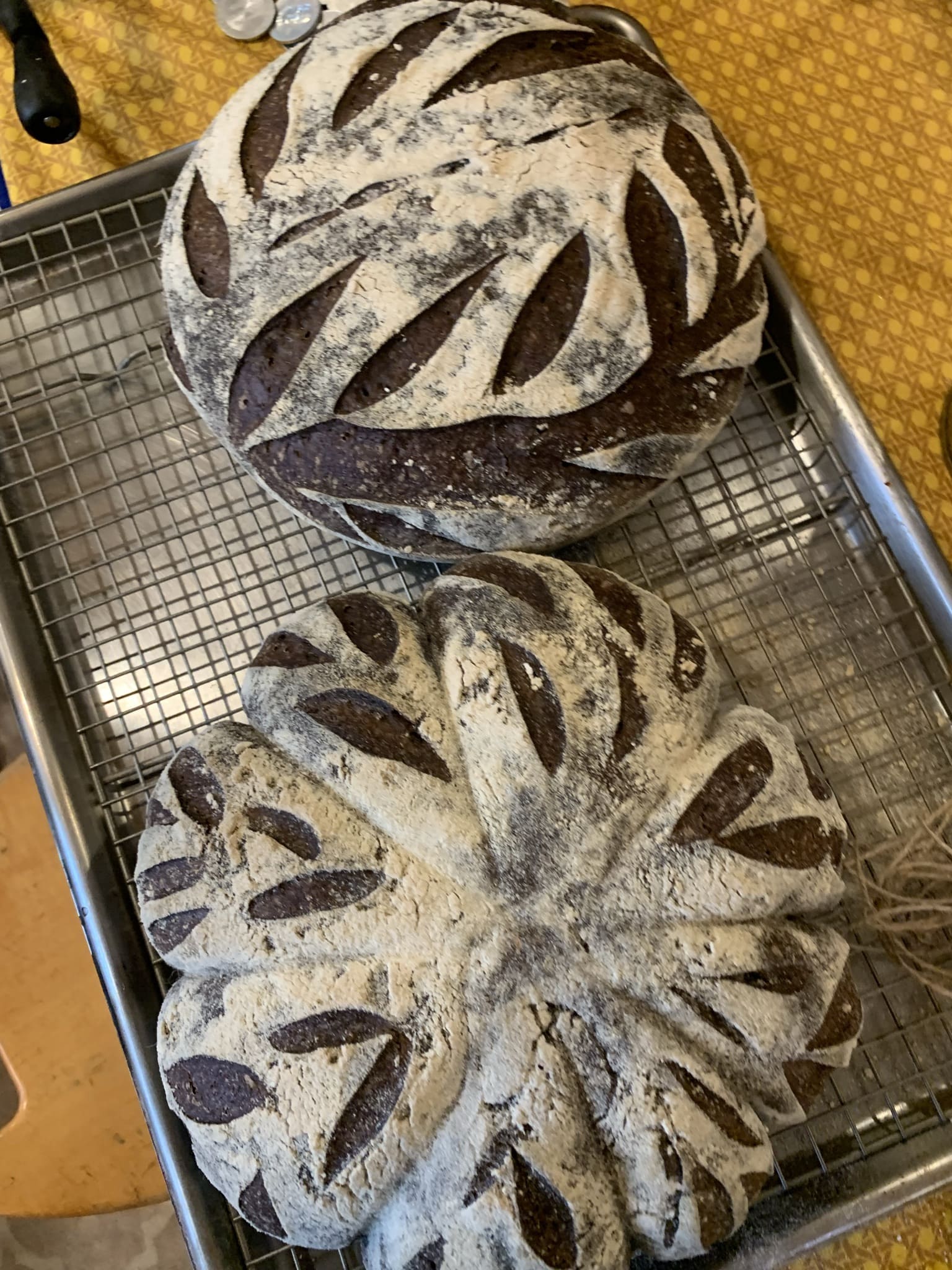 Two loaves of bread with a decorative pattern on a cooling rack.